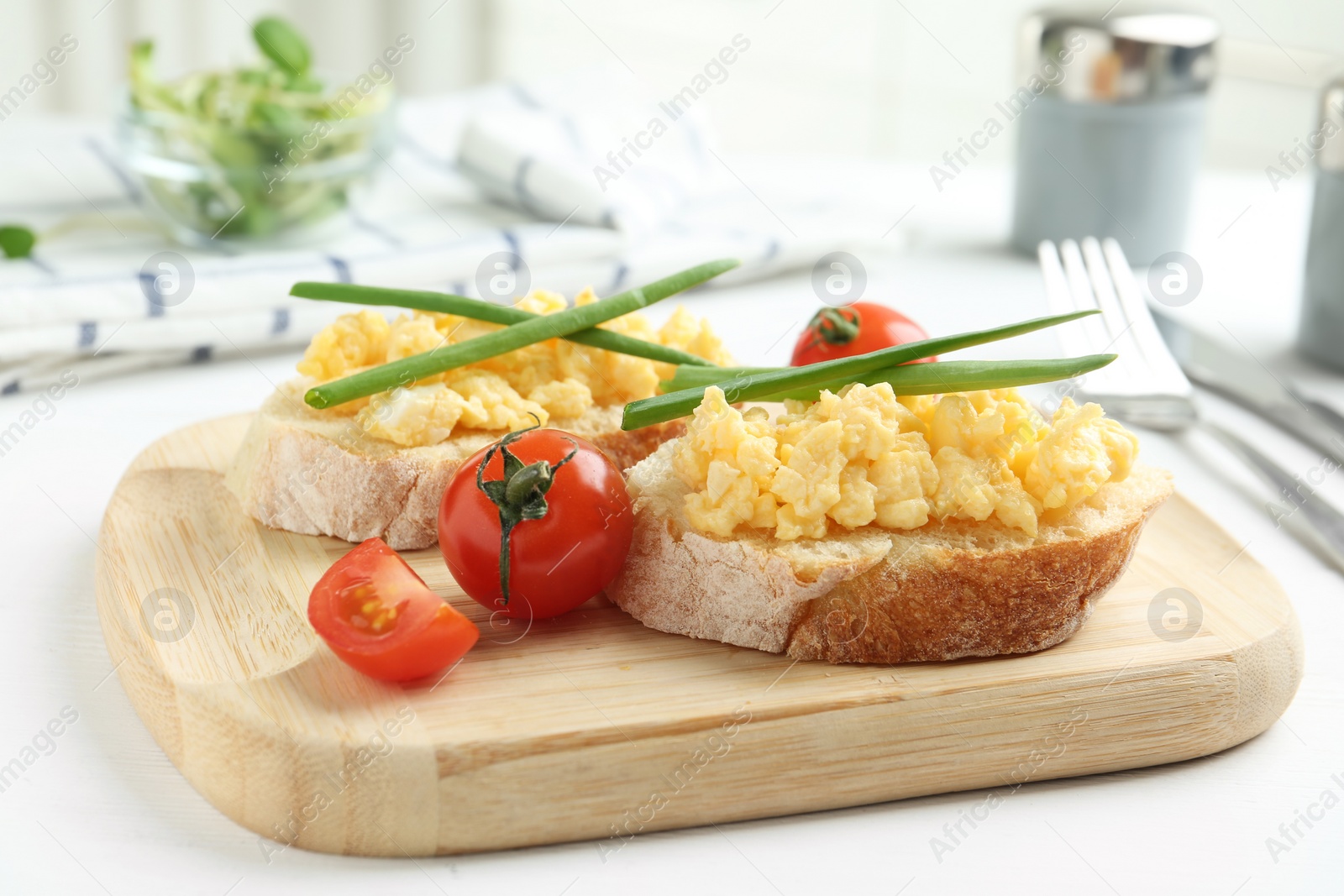 Photo of Tasty scrambled egg sandwiches on white wooden table