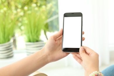 Photo of Woman holding smartphone with blank screen on blurred background. Mockup for design