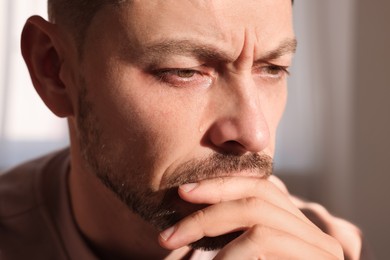 Upset man crying indoors, closeup. Loneliness concept