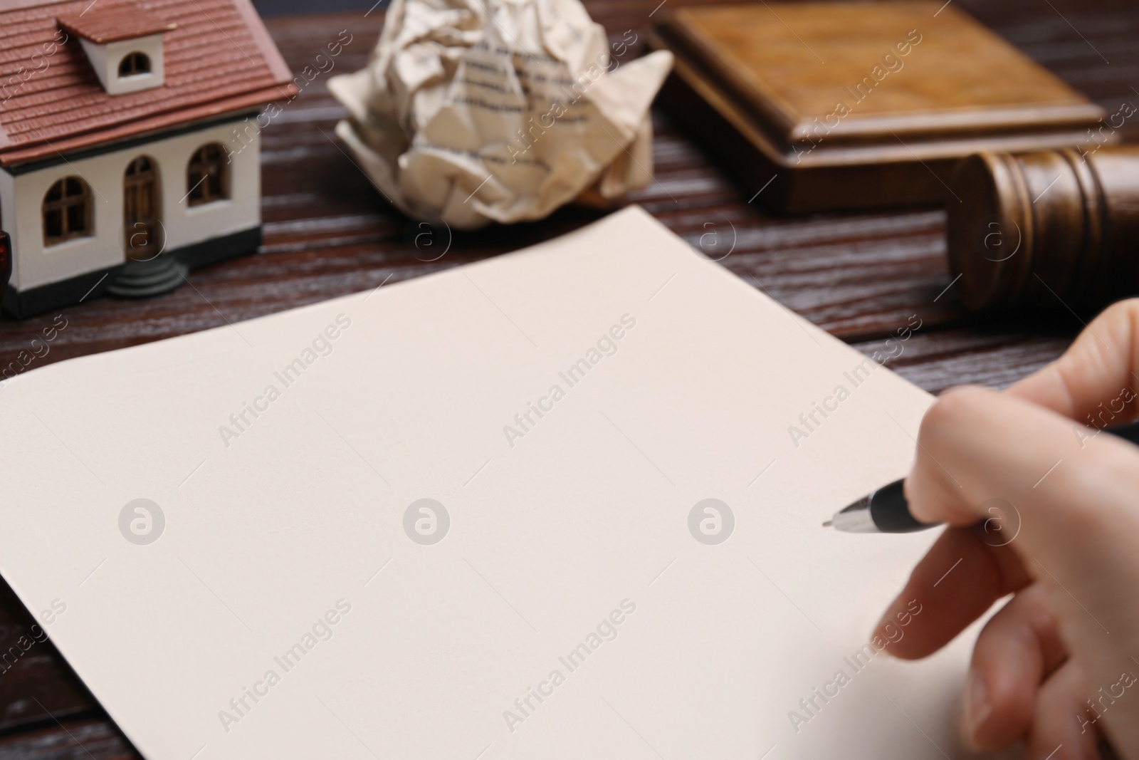 Photo of Woman signing last will and testament at wooden table, closeup