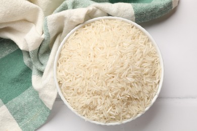 Photo of Raw basmati rice in bowl on white tiled table, top view