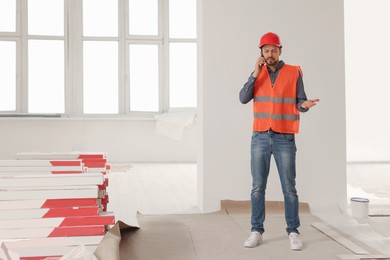 Photo of Male industrial engineer in uniform talking on phone indoors