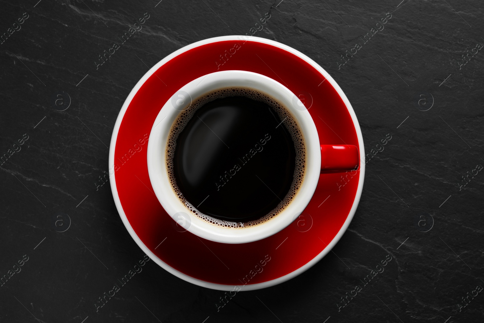 Photo of Cup with aromatic coffee on black textured table, top view
