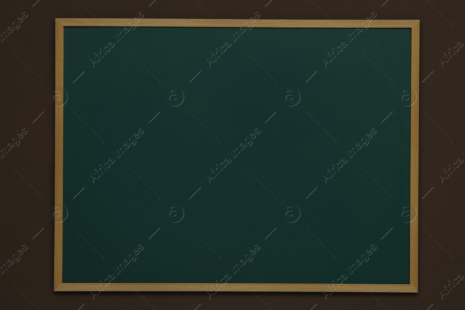 Photo of Clean green chalkboard hanging on brown wall