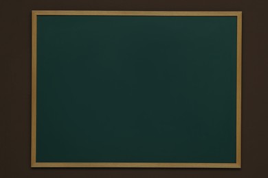 Clean green chalkboard hanging on brown wall