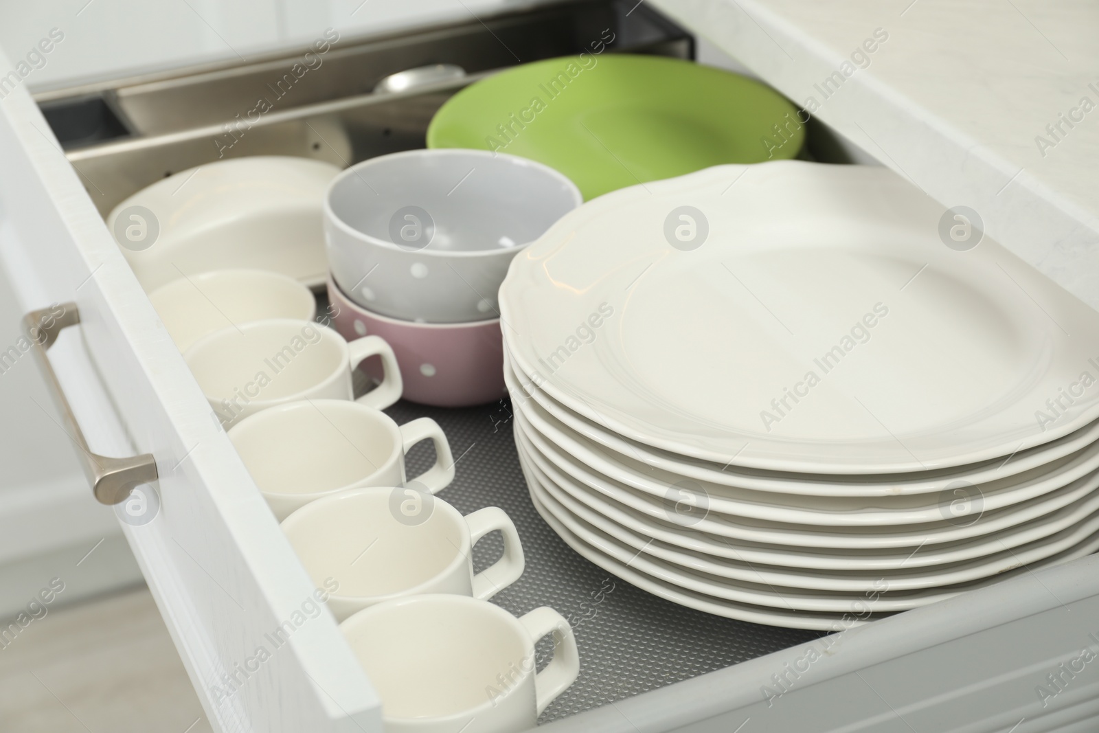 Photo of Clean plates, bowls, cups and butter dish in drawer indoors