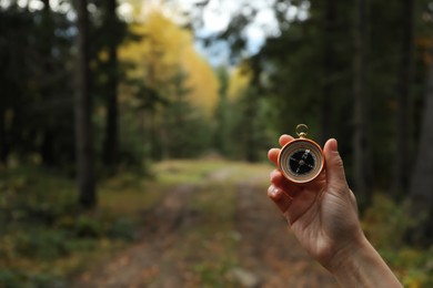 Photo of Woman using compass during hiking in forest, closeup