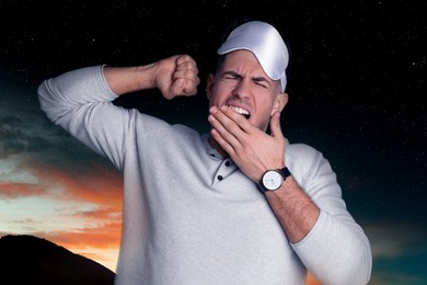 Tired man with sleeping mask and beautiful starry sky at night on background