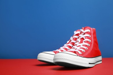 Pair of new stylish red sneakers on colorful background. Space for text