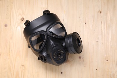 Photo of One gas mask on wooden background, top view