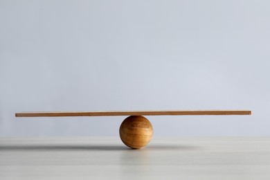 Photo of Wooden ball with small plank on table, space for text. Harmony and balance concept