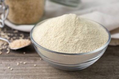 Glass bowl with quinoa flour and seeds on table, closeup