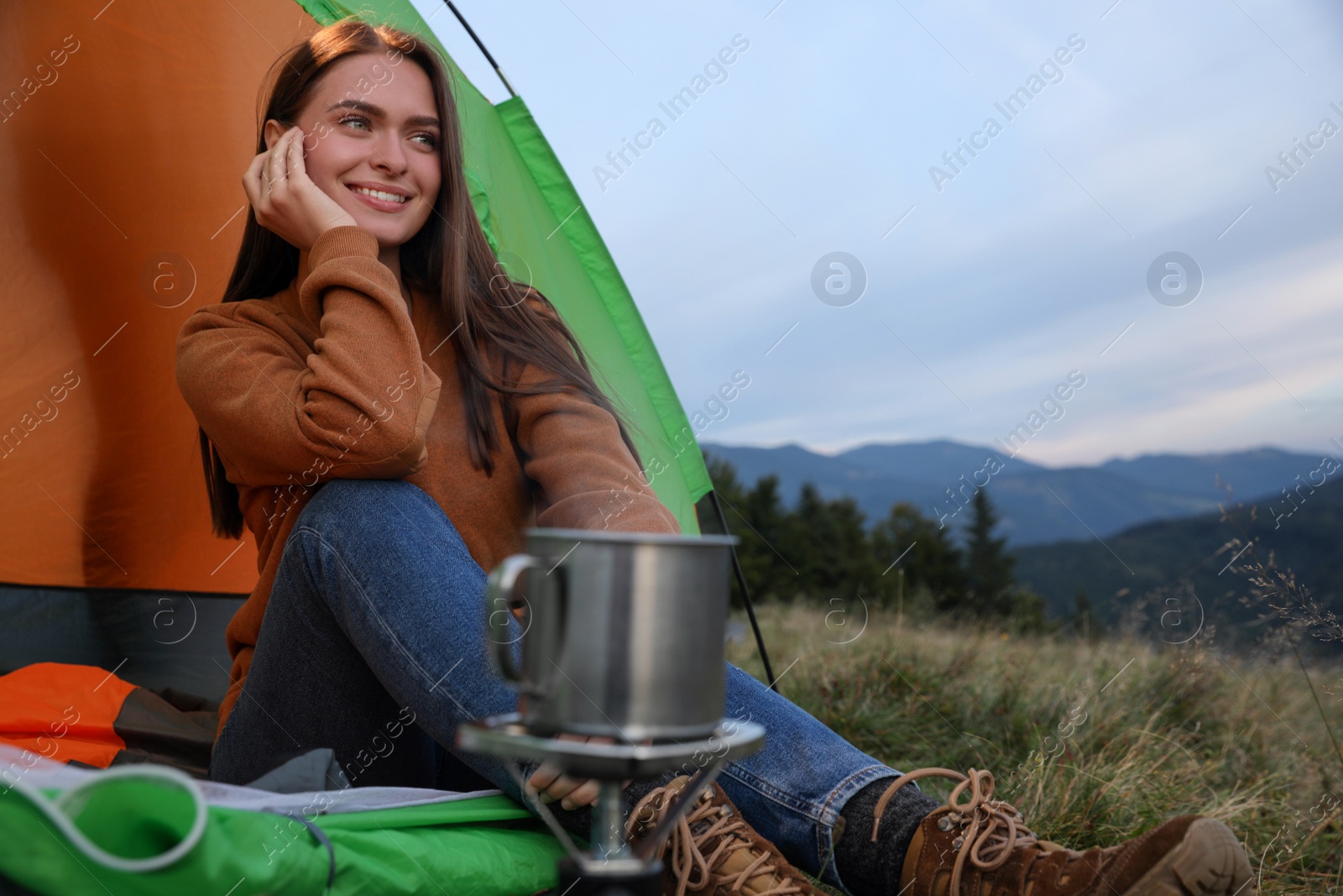 Photo of Young woman enjoying mountain landscape in camping tent