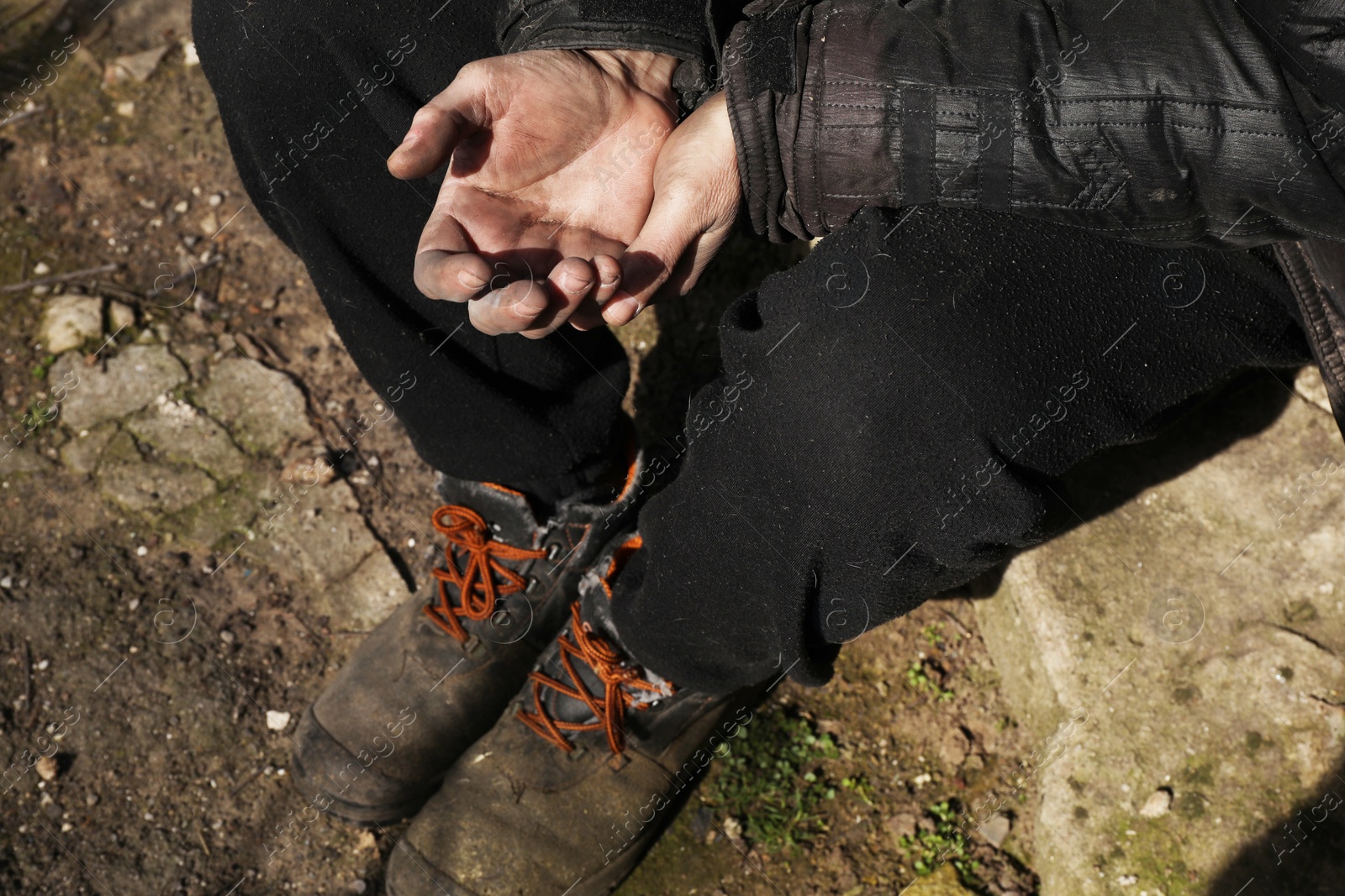 Photo of Poor homeless man with dirty hands outdoors, top view