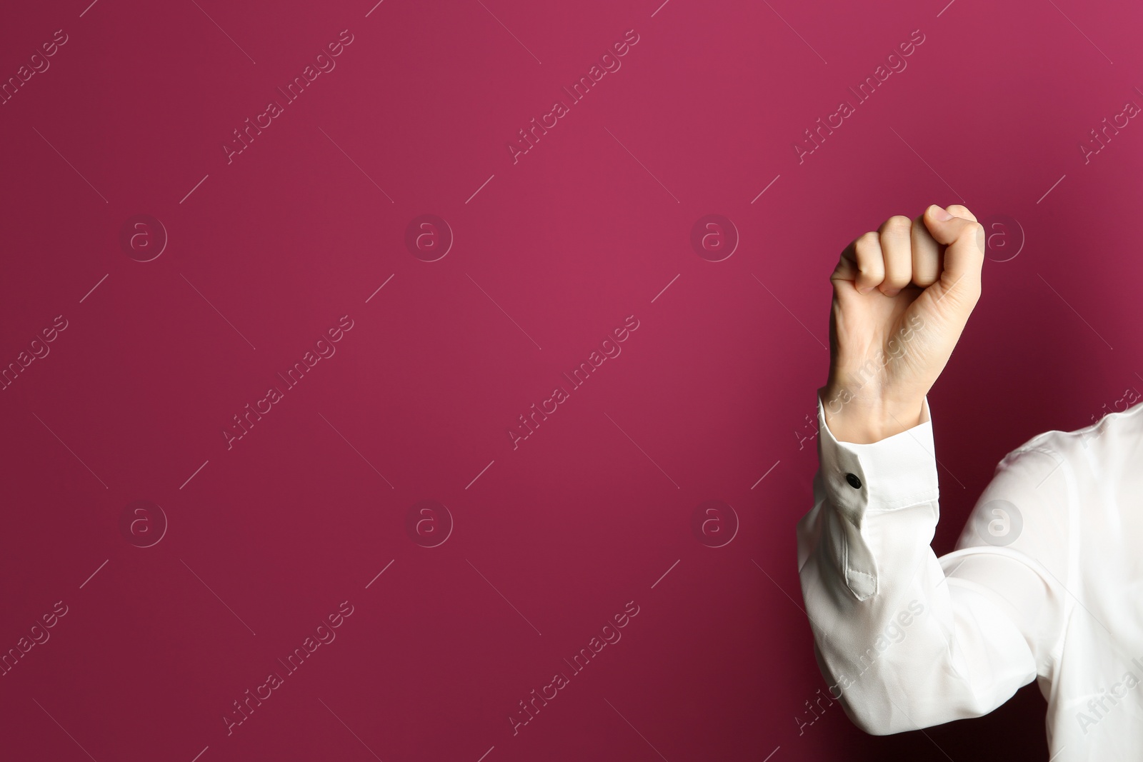 Photo of Young woman showing clenched fist on color background. Space for text