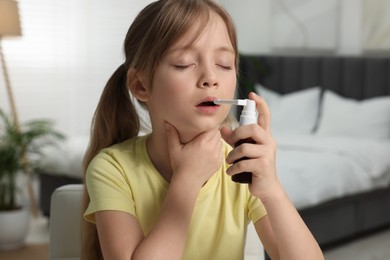 Photo of Little girl using throat spray at home