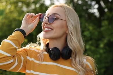 Portrait of happy young woman with headphones in park on spring day