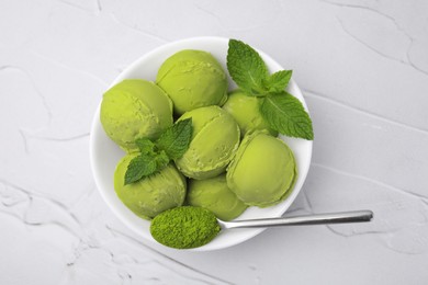 Photo of Tasty matcha ice cream and spoon with powder in bowl on white textured table, top view
