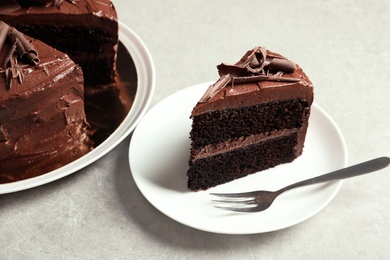 Photo of Plate with slice of tasty chocolate cake and fork on table