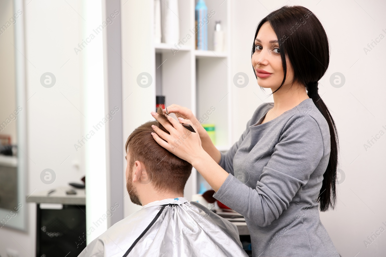 Photo of Professional female hairdresser working with client in salon