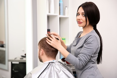 Professional female hairdresser working with client in salon