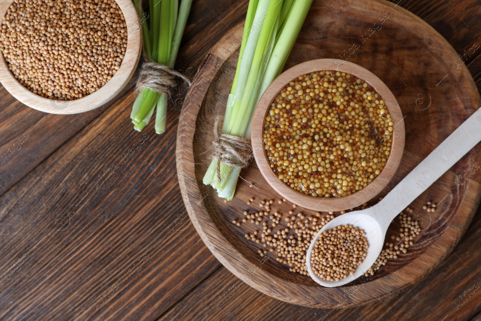 Photo of Tray with delicious whole grain mustard, seeds and fresh green onion on wooden table, flat lay