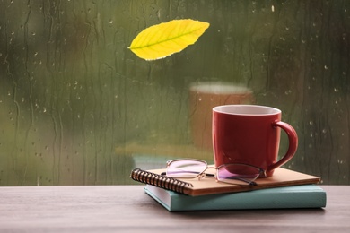 Photo of Composition with cup of drink and autumn leaf on windowsill. Rainy weather