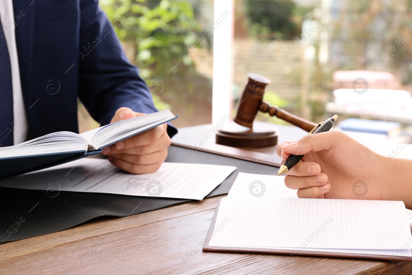 Photo of Lawyer working with client at table in office, focus on hands