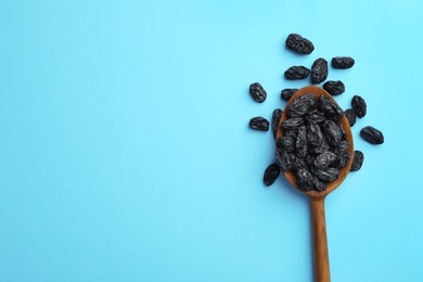 Photo of Spoon of raisins on color background, top view with space for text. Dried fruit as healthy snack