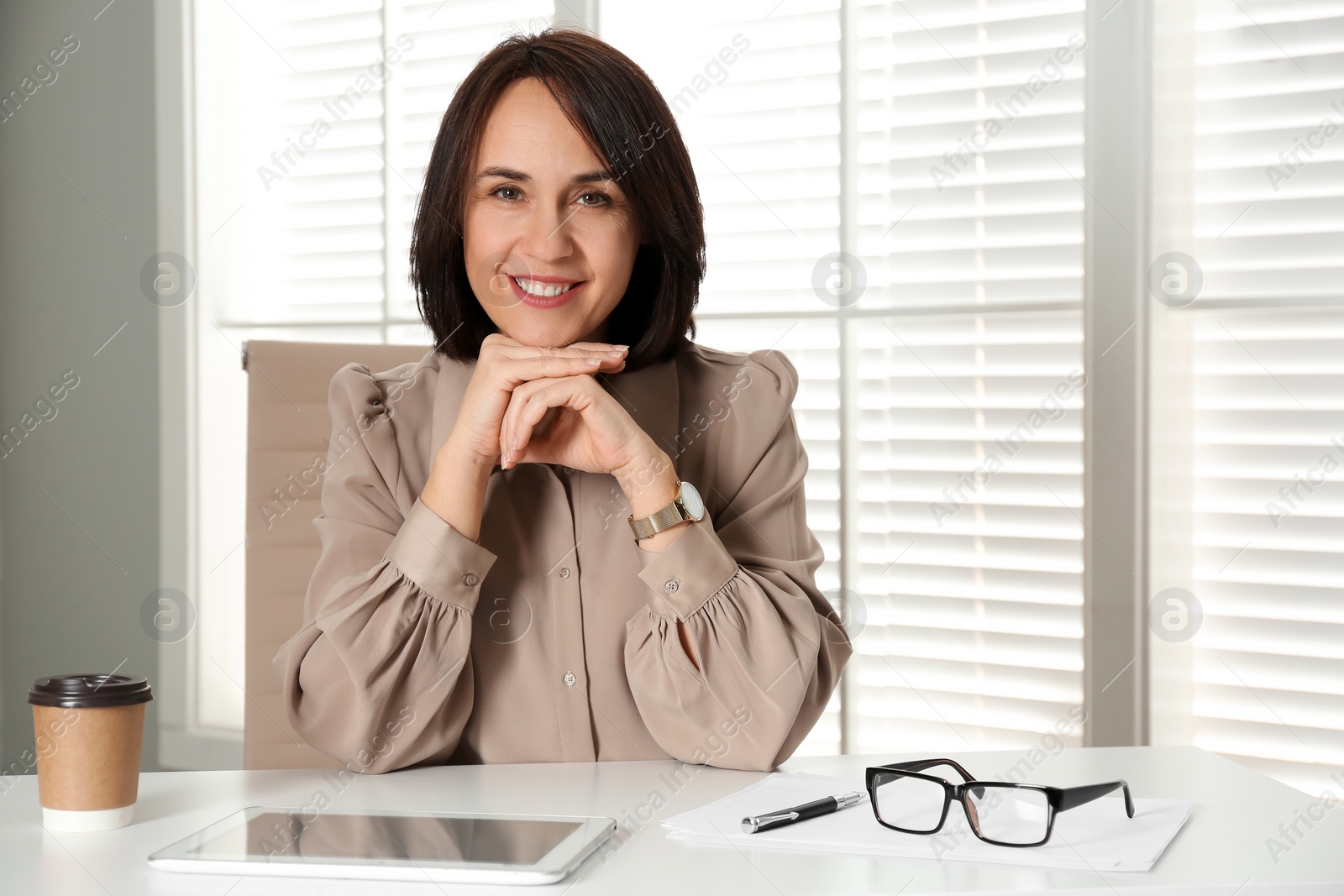 Photo of Mature businesswoman sitting at table in office