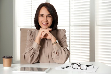 Photo of Mature businesswoman sitting at table in office