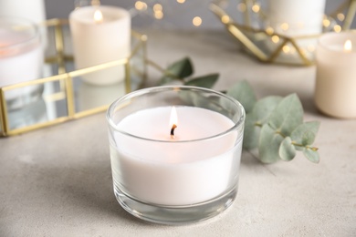 Photo of Burning aromatic candle and eucalyptus branch on table