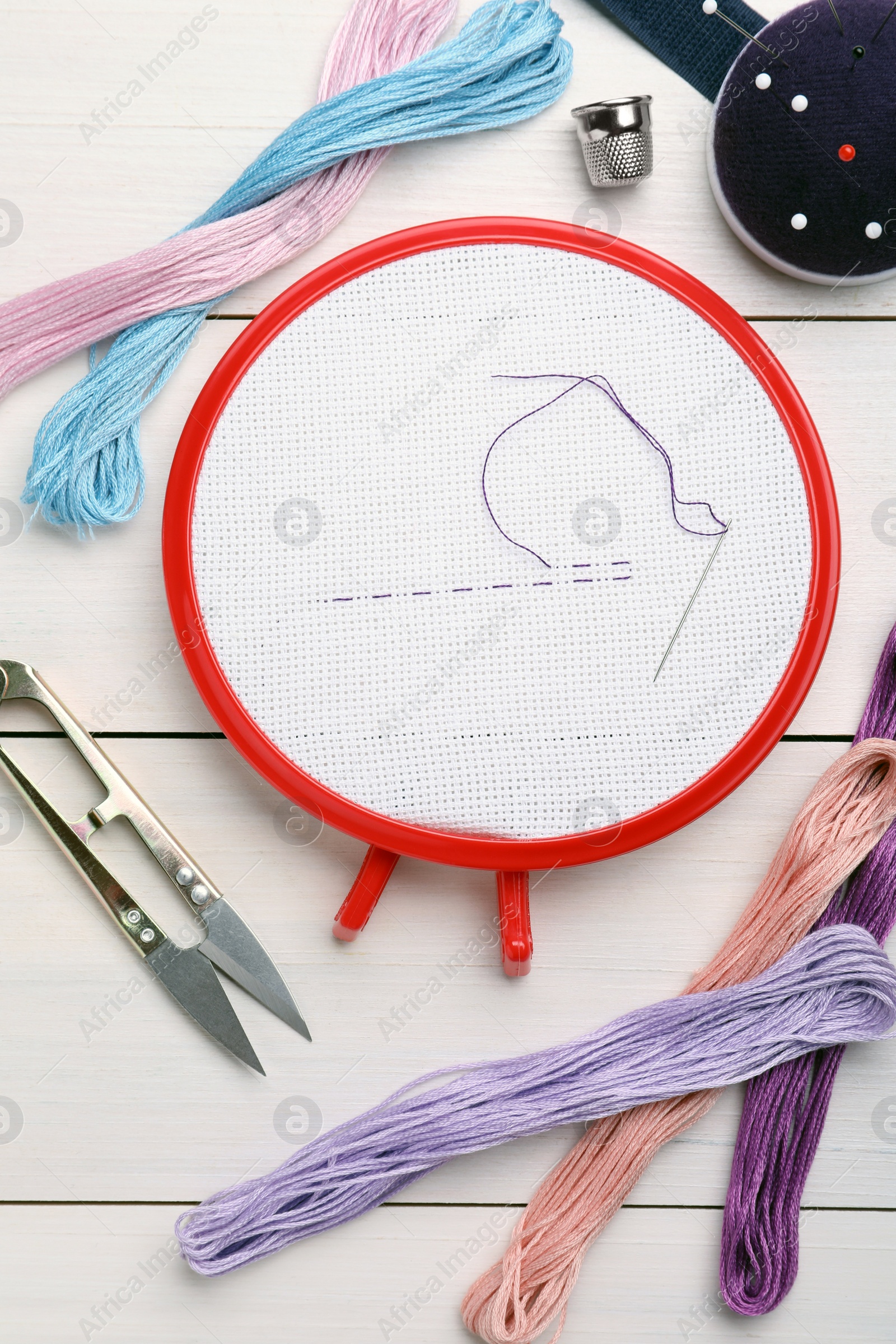 Photo of Set of embroidery equipment on white wooden table, flat lay