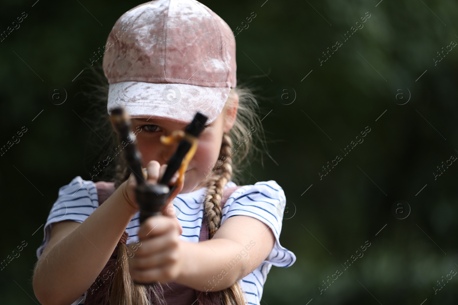 Photo of Little girl playing with slingshot outdoors. Space for text