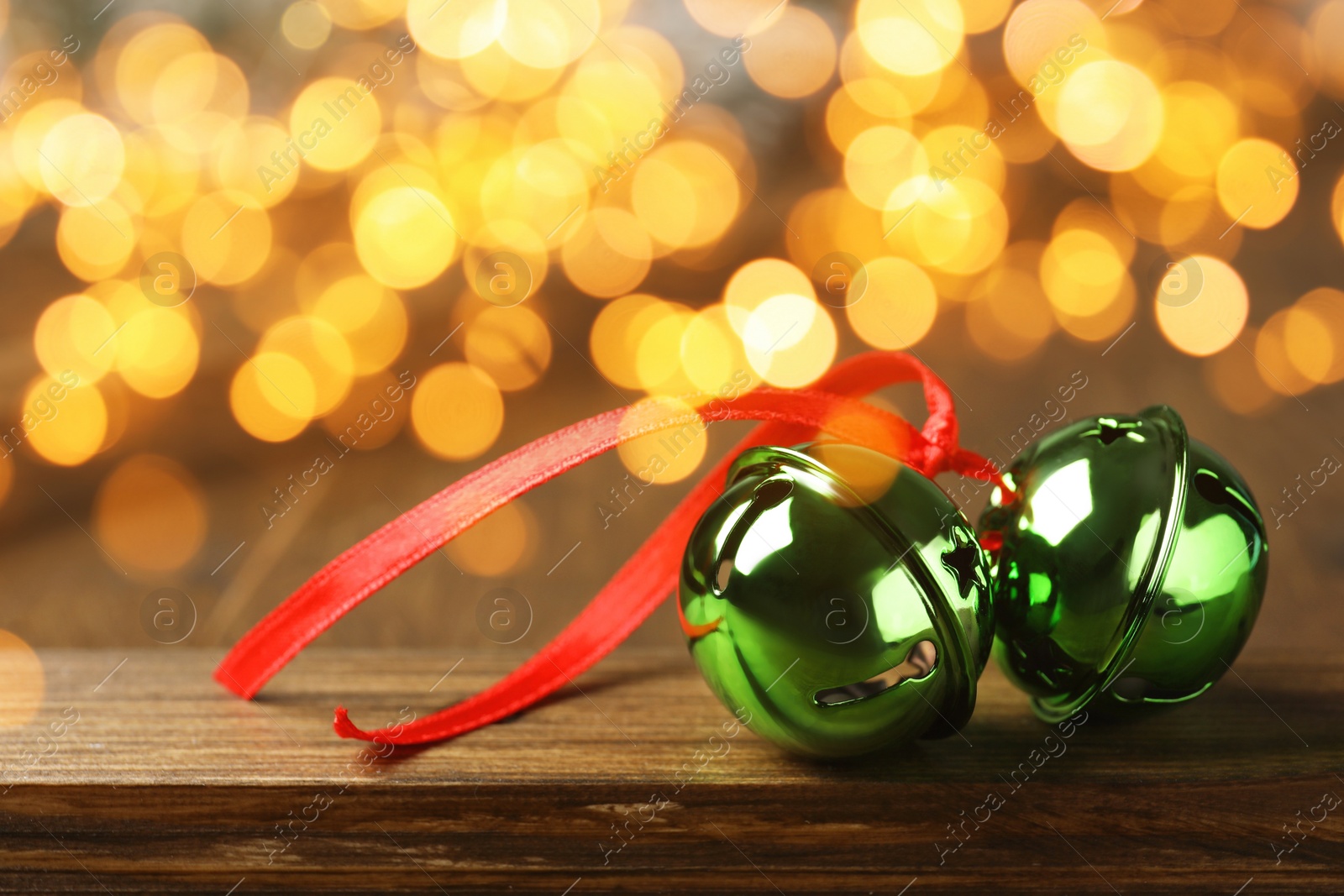 Image of Christmas music. Jingle bells on wooden table, bokeh effect