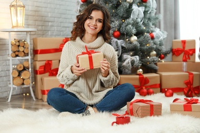 Image of Happy young woman with Christmas gift at home
