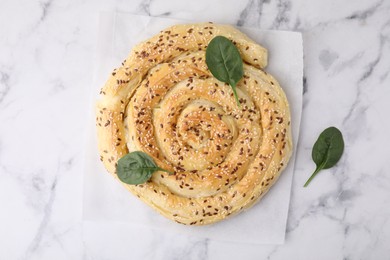 Photo of Delicious puff pastry with spinach on white marble table, top view