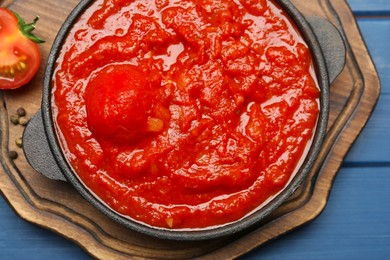 Homemade tomato sauce in bowl on blue wooden table, top view