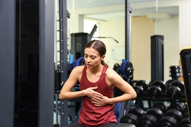 Photo of Young woman having heart attack in gym