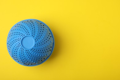 Photo of Laundry dryer ball on yellow background, top view. Space for text