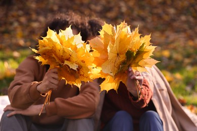 Photo of Young couple in autumn park, focus on dry leaves. Dating agency