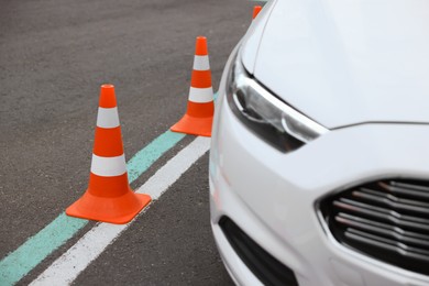 Photo of Modern car on test track with traffic cones, closeup. Driving school