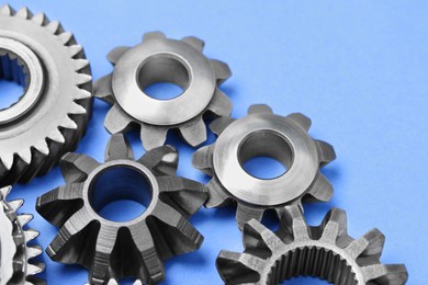 Photo of Different stainless steel gears on light blue background, closeup