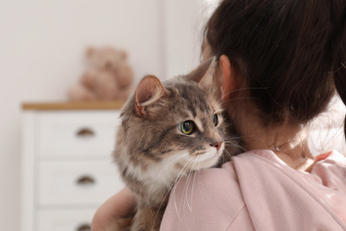 Little girl with cute cat at home. First pet