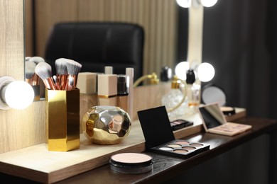 Photo of Makeup brushes and cosmetic products on dressing table in room