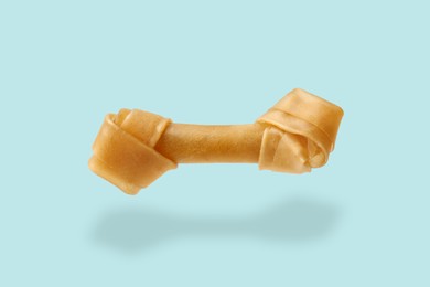 Image of Bone dog treat in air on light blue background