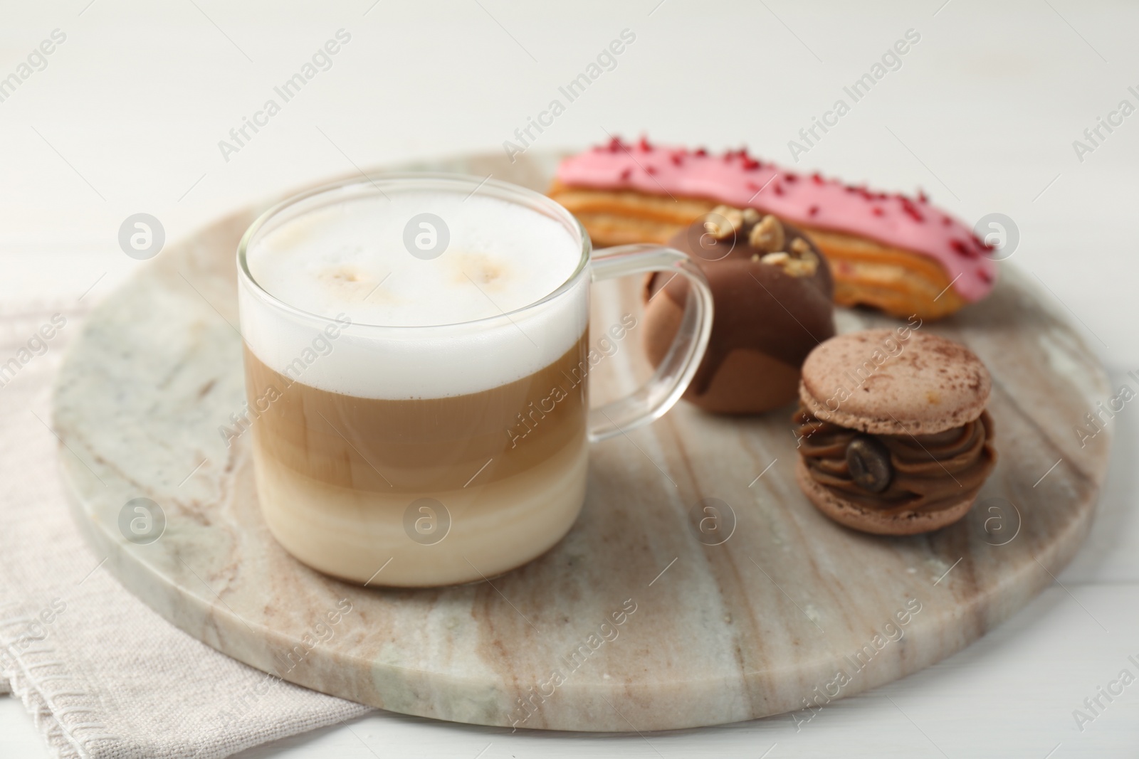 Photo of Aromatic coffee in cup, tasty macarons and eclair on white table