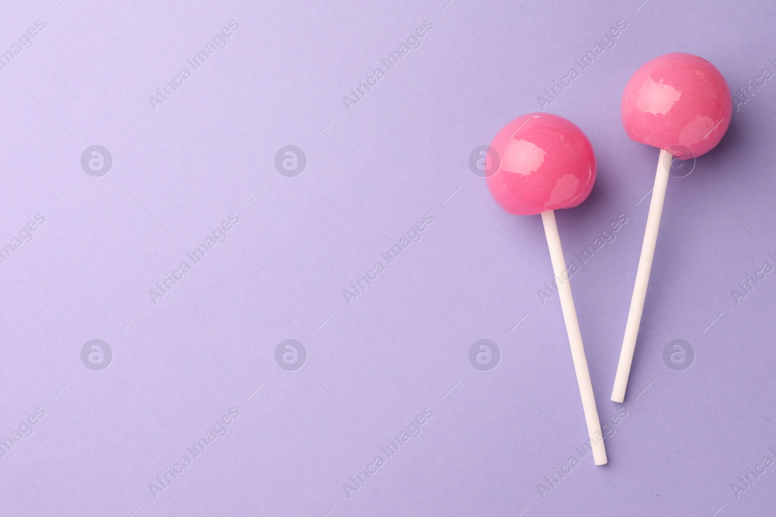 Photo of Tasty lollipops on violet background, flat lay. Space for text