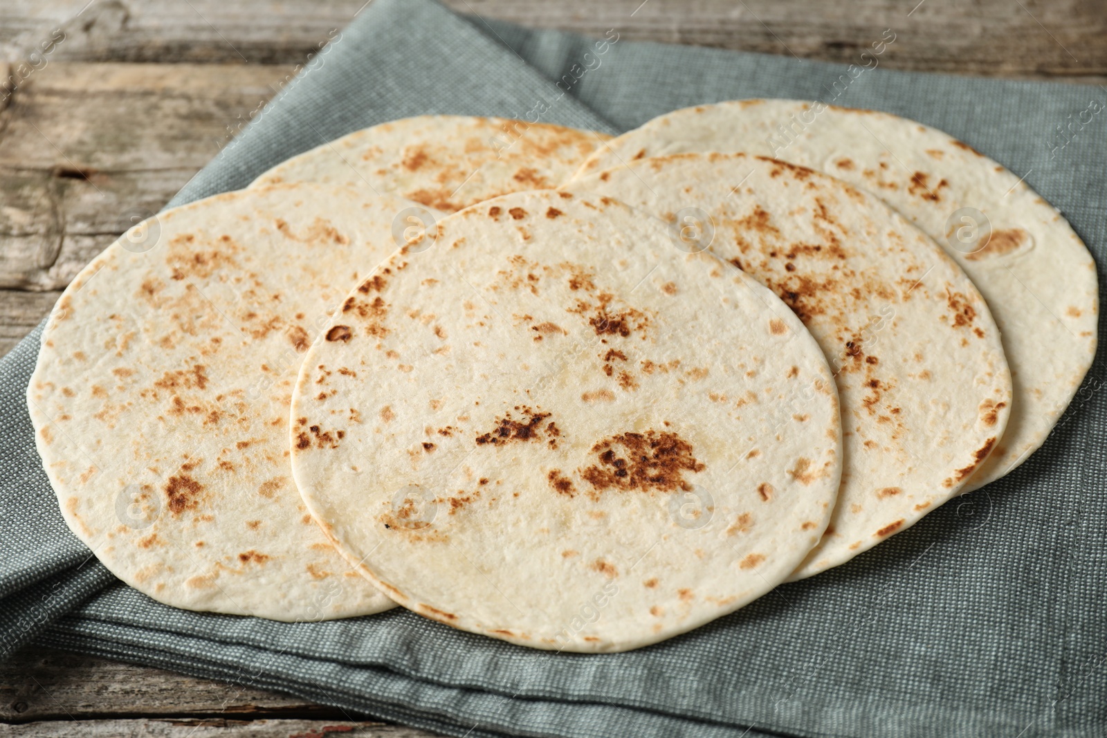 Photo of Many tasty homemade tortillas on wooden table