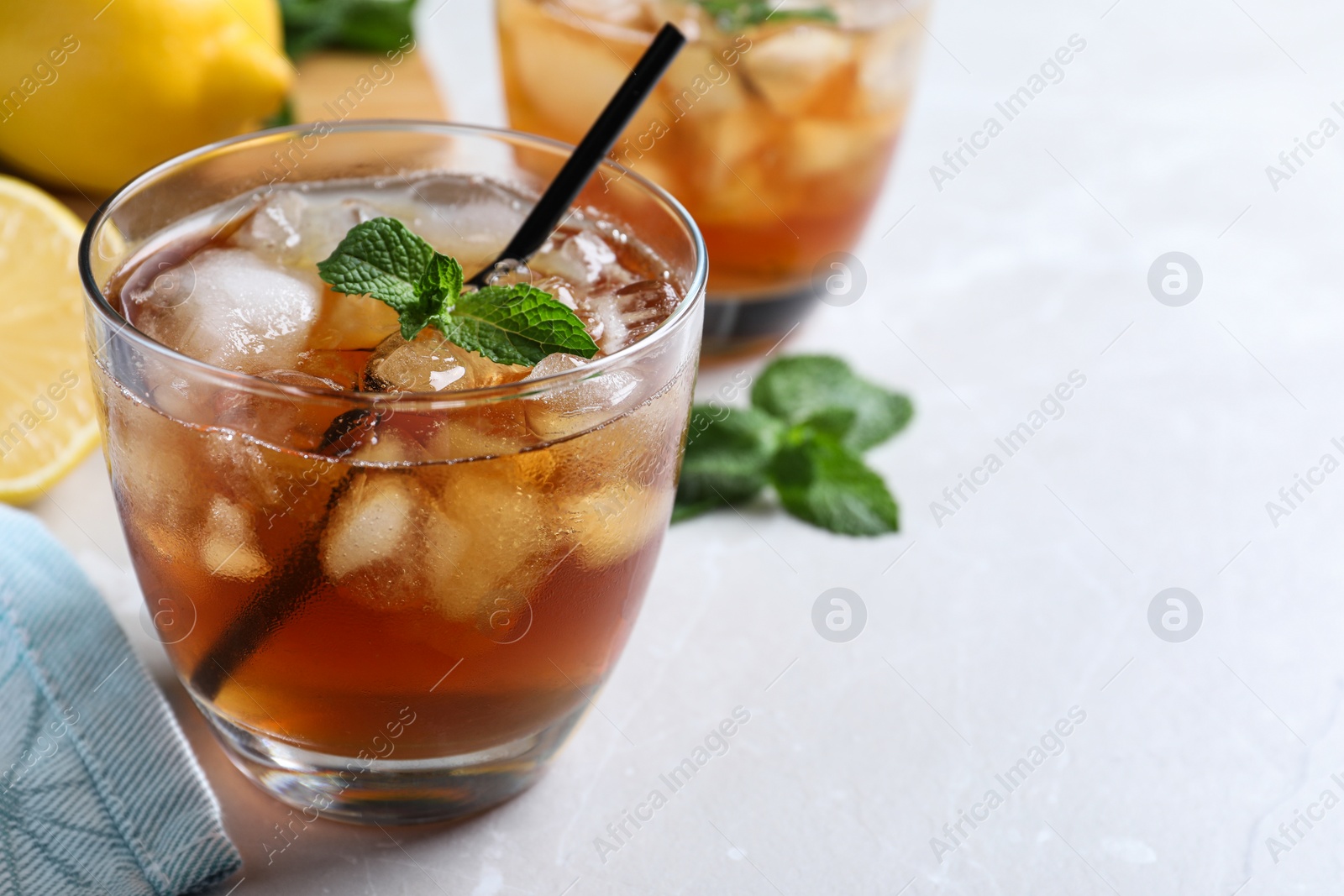 Photo of Delicious iced tea in glass on light table, space for text